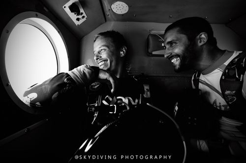 two friends having fun inside of a plane before skydiving